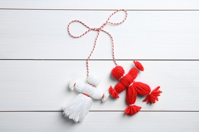 Photo of Traditional martisor shaped as man and woman on white wooden background, top view. Beginning of spring celebration