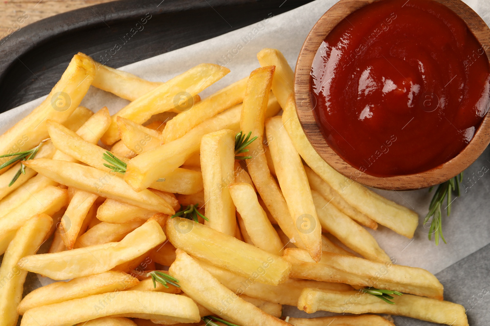 Photo of Delicious french fries served with ketchup on board, flat lay