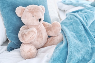 Photo of Cute teddy bear sitting on bed indoors. Space for text