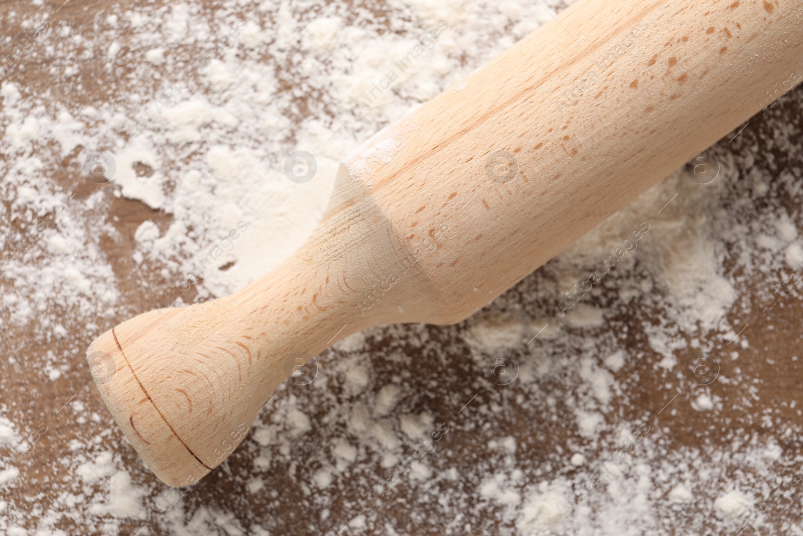 Photo of Scattered flour and rolling pin on wooden table, top view