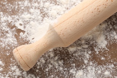 Photo of Scattered flour and rolling pin on wooden table, top view