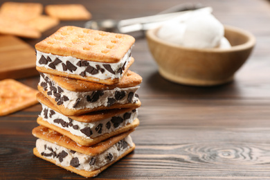 Photo of Sweet delicious ice cream cookie sandwiches on wooden table. Space for text