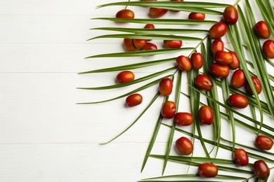 Photo of Palm oil fruits on white wooden table, flat lay. Space for text