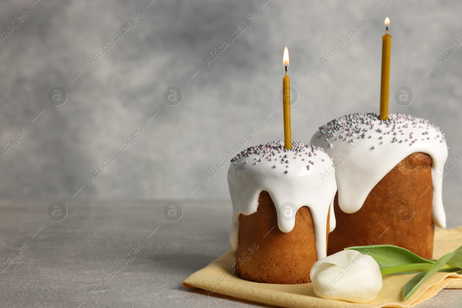 Photo of Tasty Easter cakes and tulip flower on grey table. Space for text