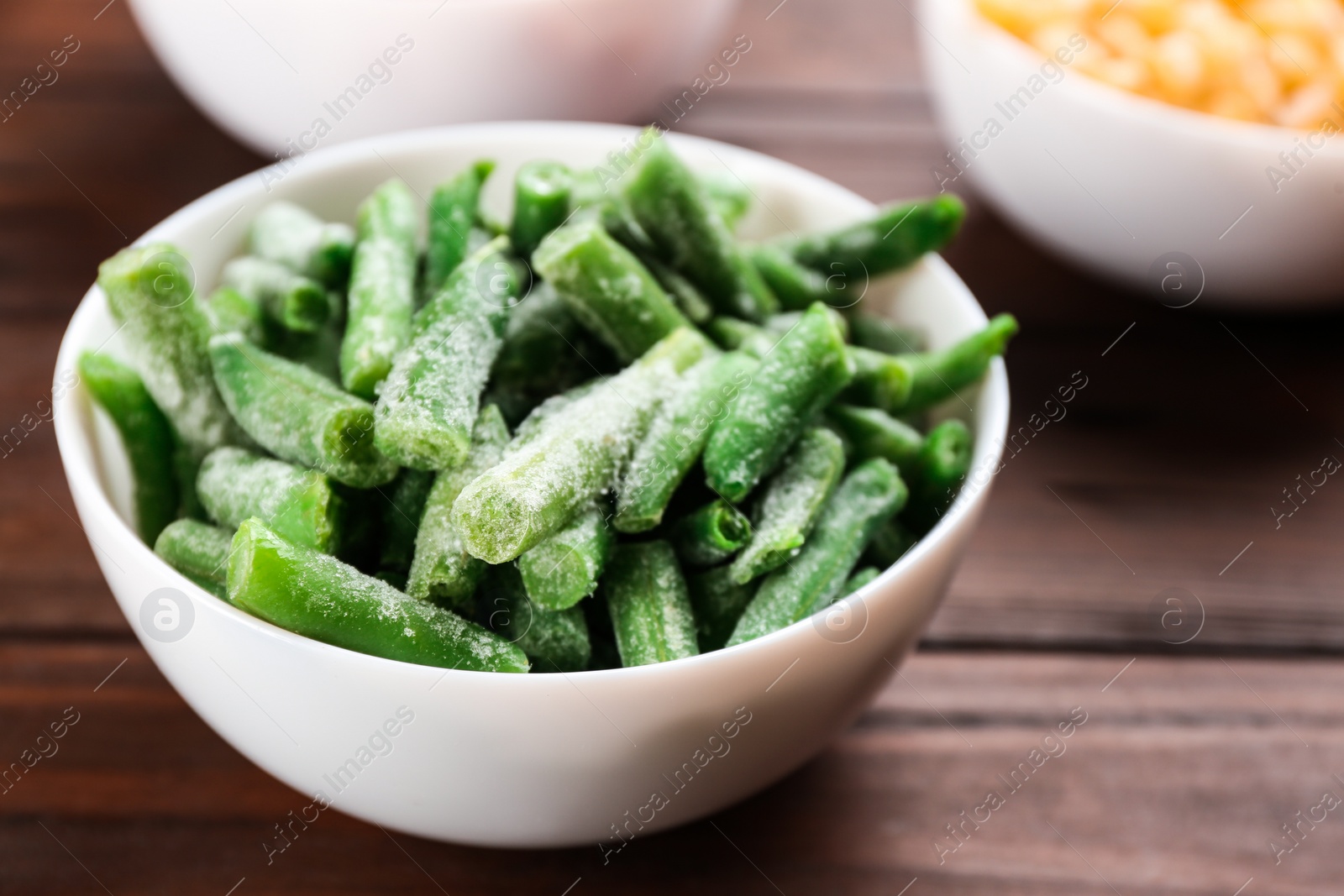 Photo of Frozen cut green beans on wooden table, closeup. Vegetable preservation