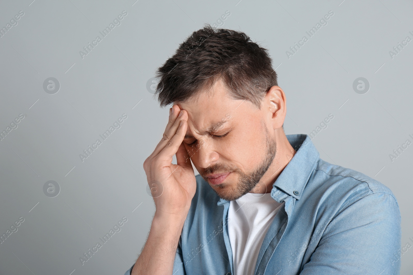 Photo of Man suffering from terrible migraine on light grey background