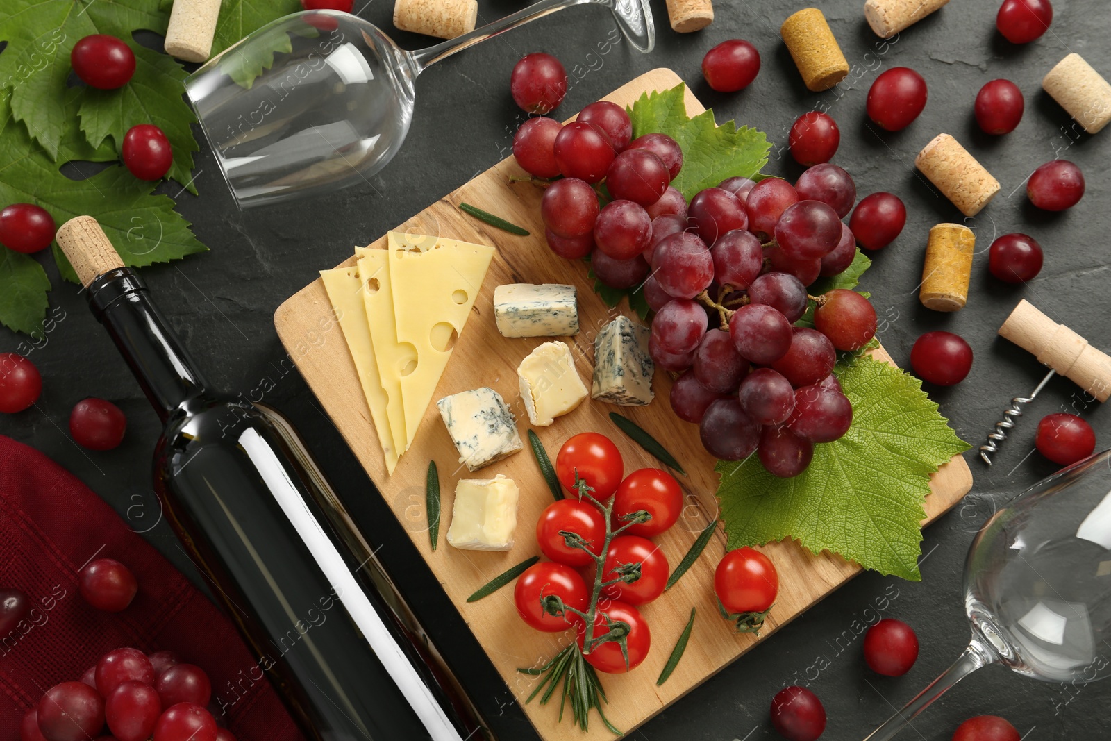 Photo of Tasty red wine and snacks on black table, flat lay