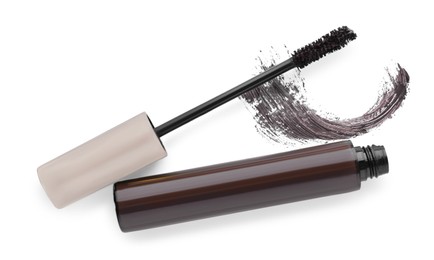 Photo of Tube, brush and brown mascara stroke on white background, top view