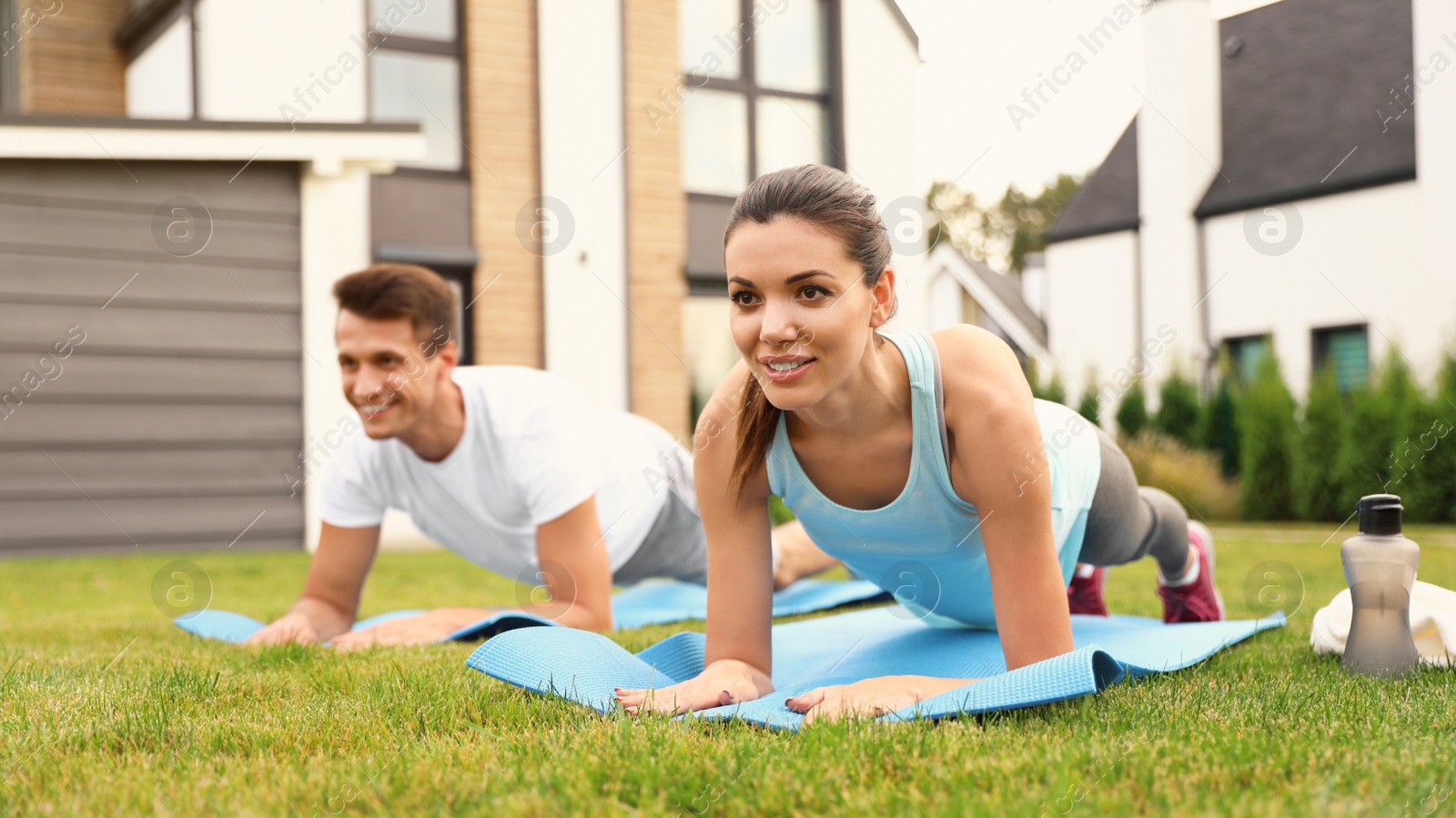 Photo of Sporty couple practicing morning yoga at backyard. Healthy lifestyle