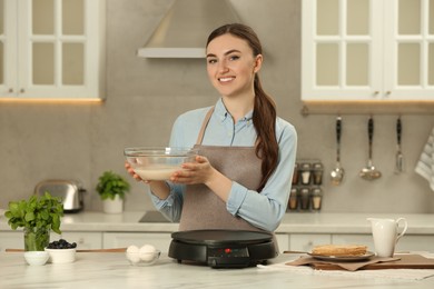 Photo of Happy woman with dough for crepes at white marble table in kitchen