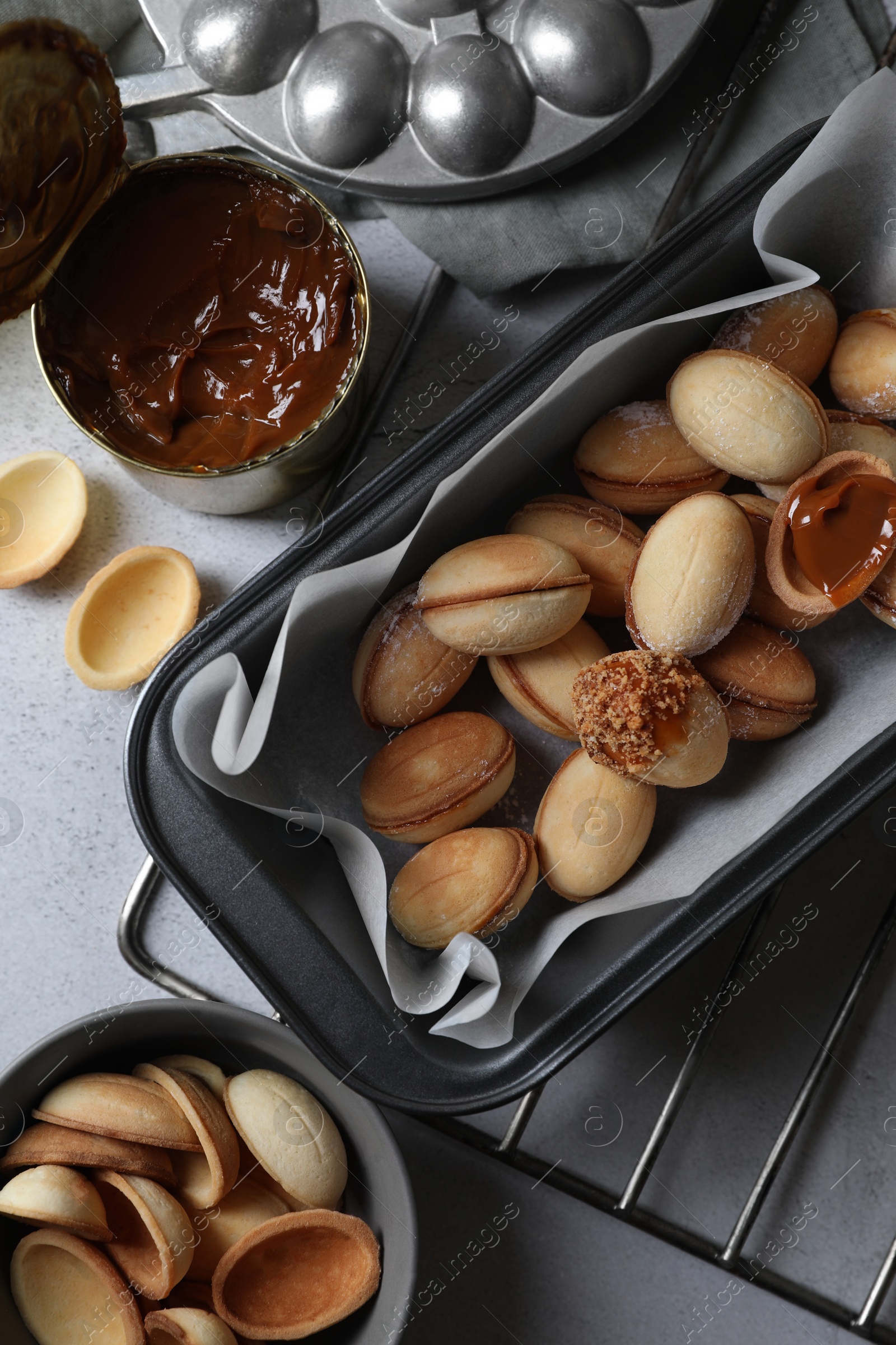 Photo of Delicious walnut shaped cookies with condensed milk on grey table, flat lay