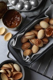 Delicious walnut shaped cookies with condensed milk on grey table, flat lay