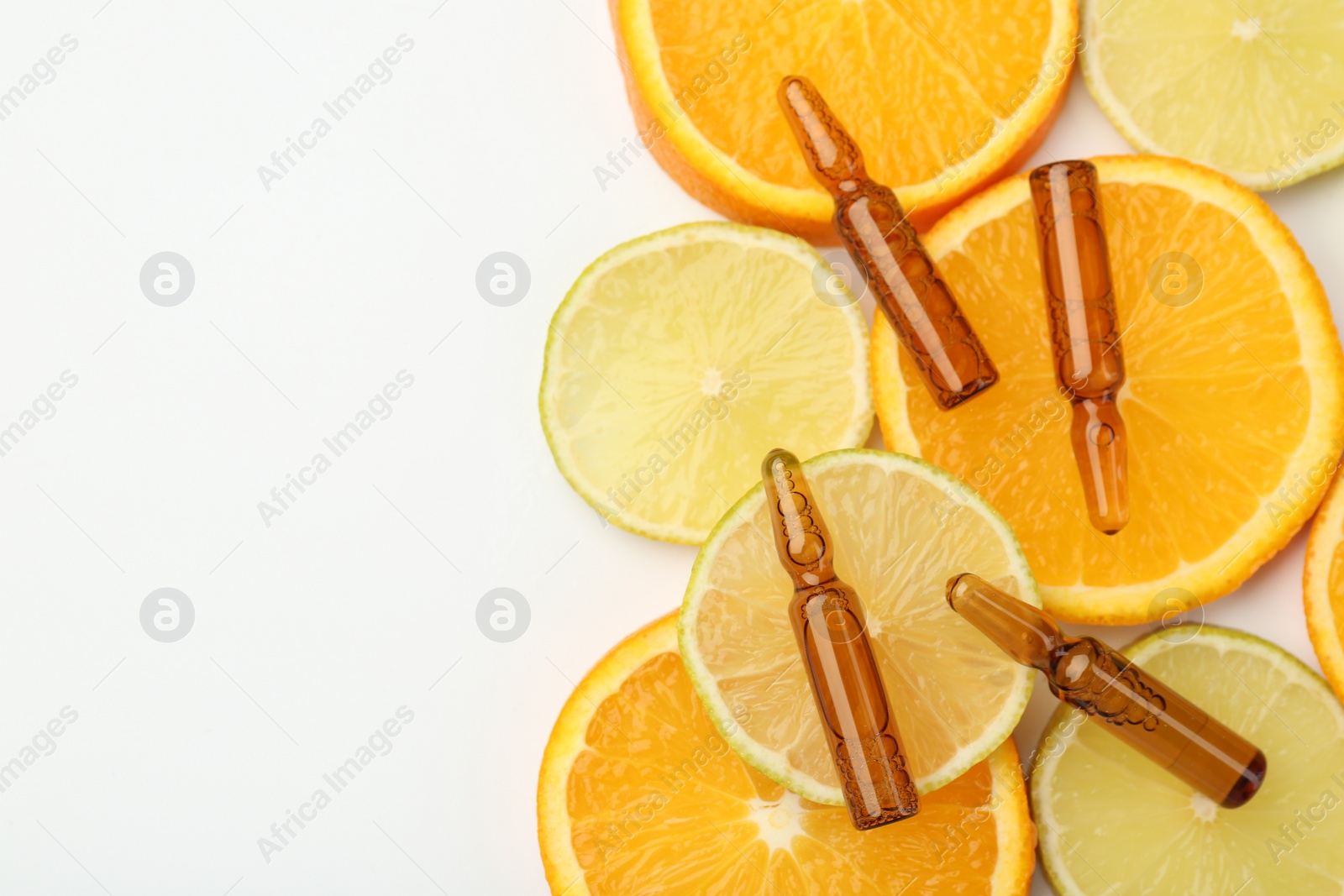 Photo of Skincare ampoules with vitamin C, lemon and orange slices on white background, flat lay. Space for text