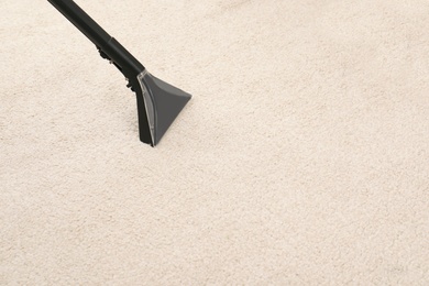 Photo of Removing dirt from carpet with vacuum cleaner indoors, closeup. Space for text