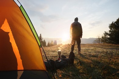 Photo of People near camping tent in mountains at sunset, back view