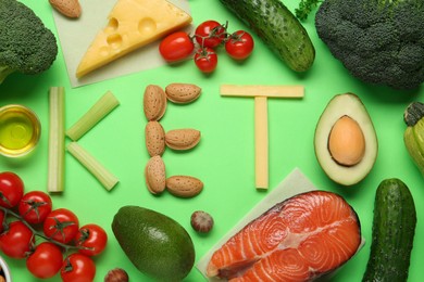 Photo of Word Keto made with products surrounded by different food on light green background, flat lay