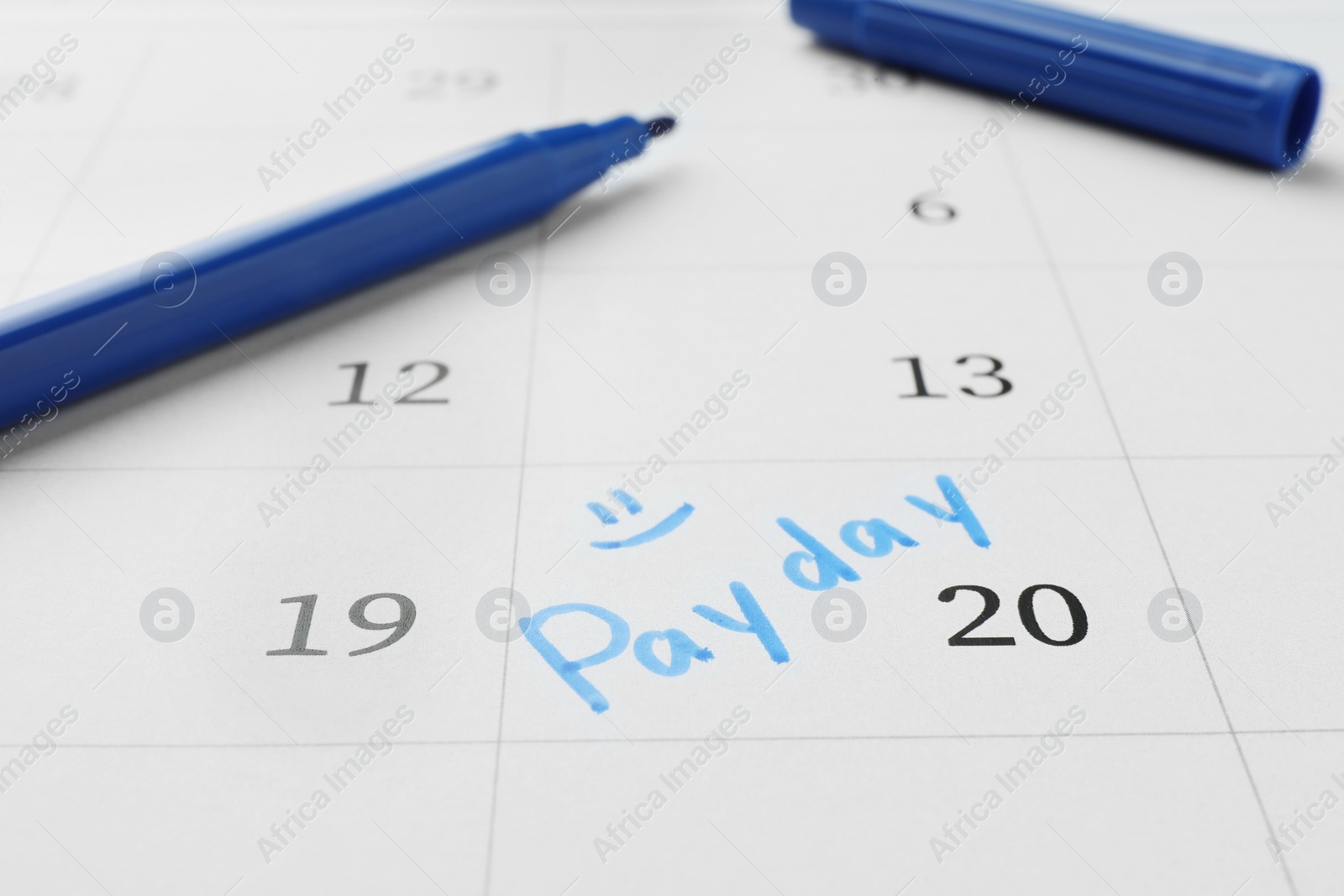 Photo of Blue felt pen on calendar page with marked payday date, closeup