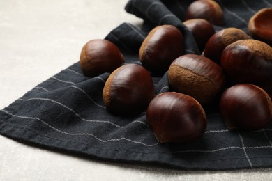 Photo of Roasted edible sweet chestnuts on light table, closeup