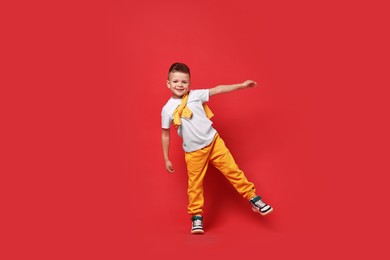 Photo of Happy little boy dancing on red background