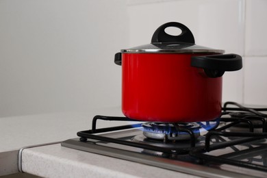 Photo of Red pot on stylish kitchen stove with burning gas, space for text