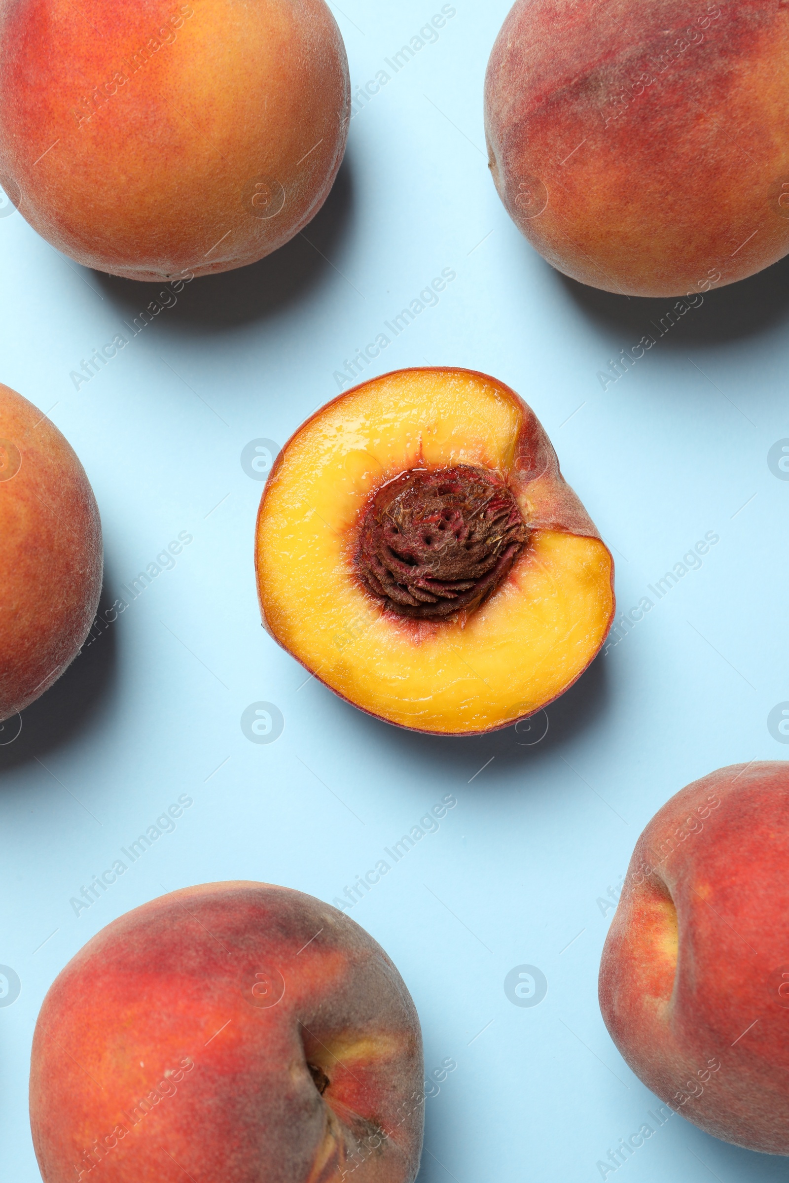 Photo of Cut and whole fresh ripe peaches on light blue background, flat lay