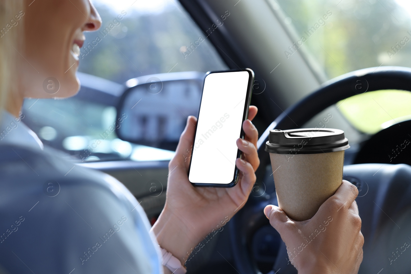 Photo of Coffee to go. Woman with paper cup of drink and smartphone in car, closeup