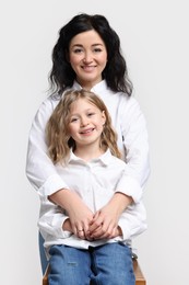 Beautiful mother with little daughter on white background