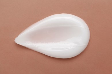 Photo of Body cream sample on orange background, closeup. Cosmetic product