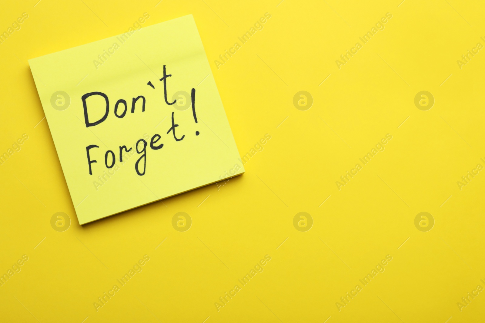 Photo of Paper note with phrase Don' t Forget on yellow background, top view. Space for text