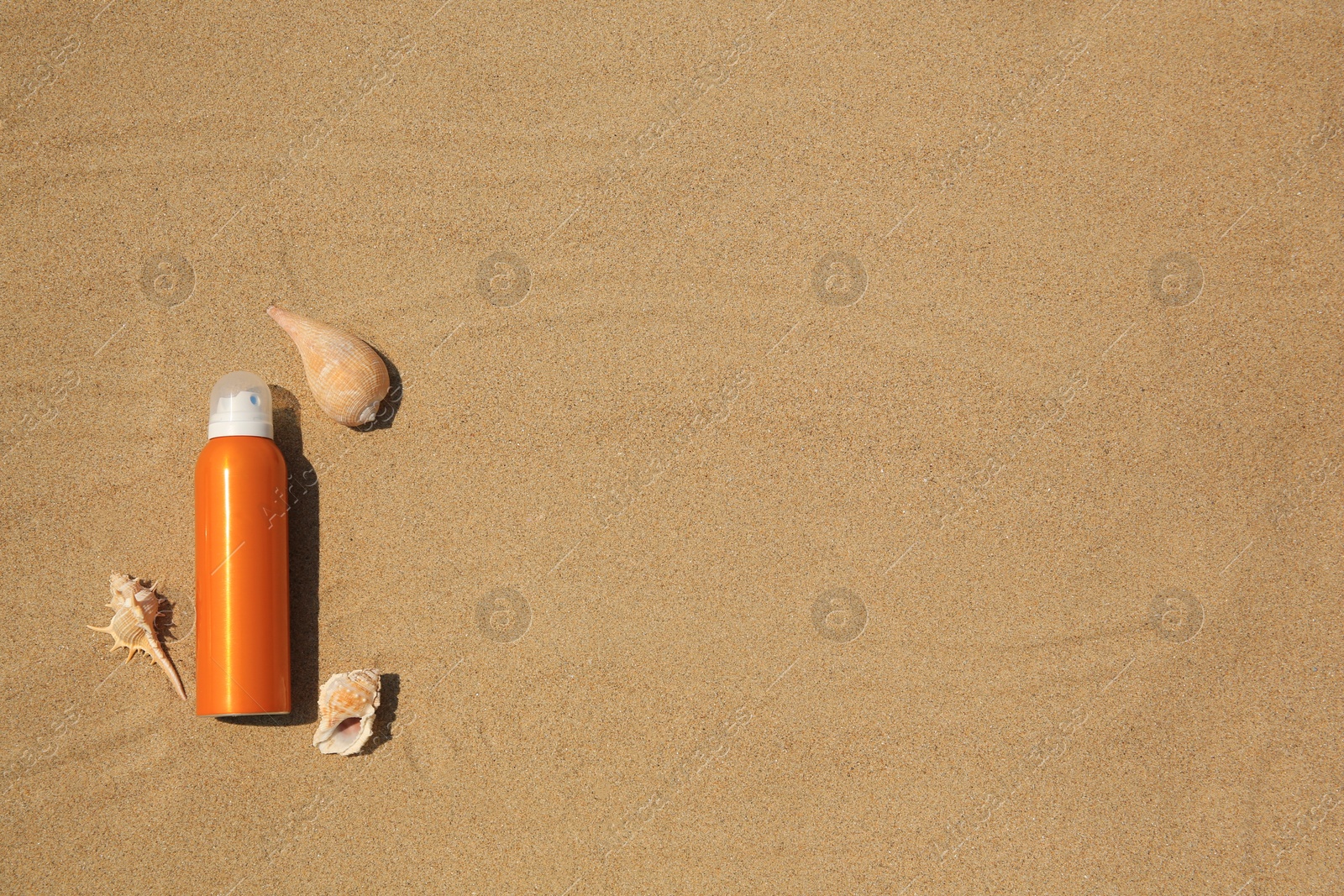 Photo of Sunscreen and seashells on sand, flat lay with space for text. Sun protection care