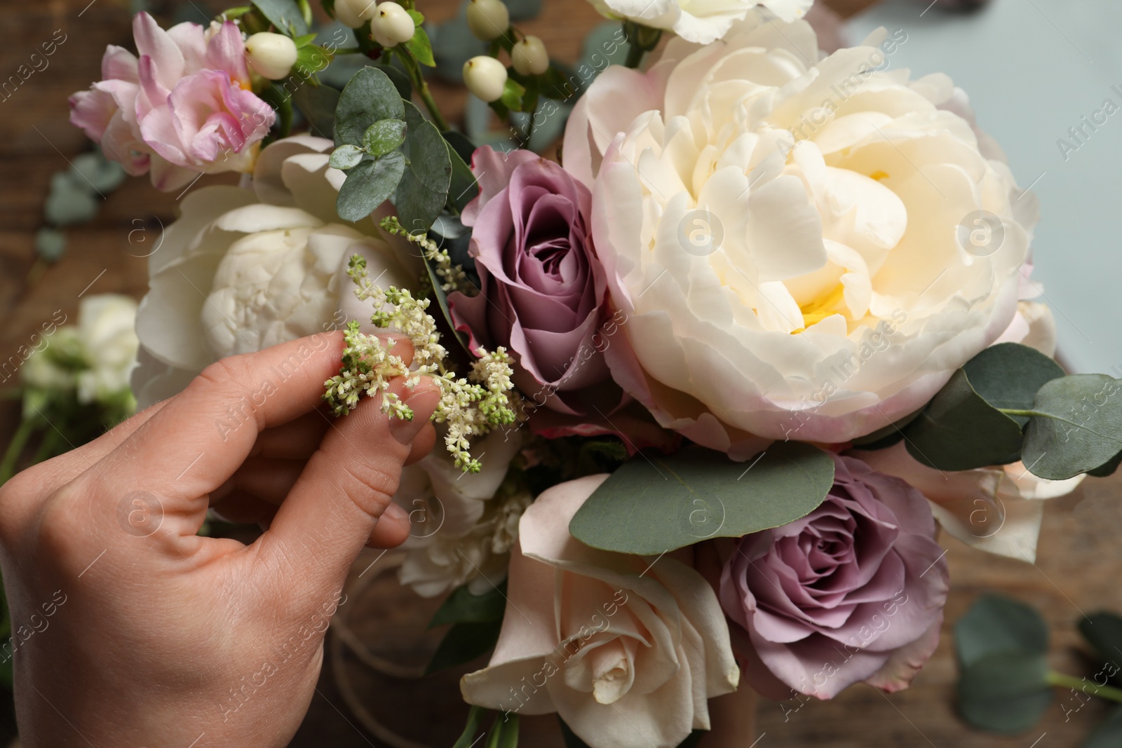 Photo of Florist creating beautiful bouquet at table, top view