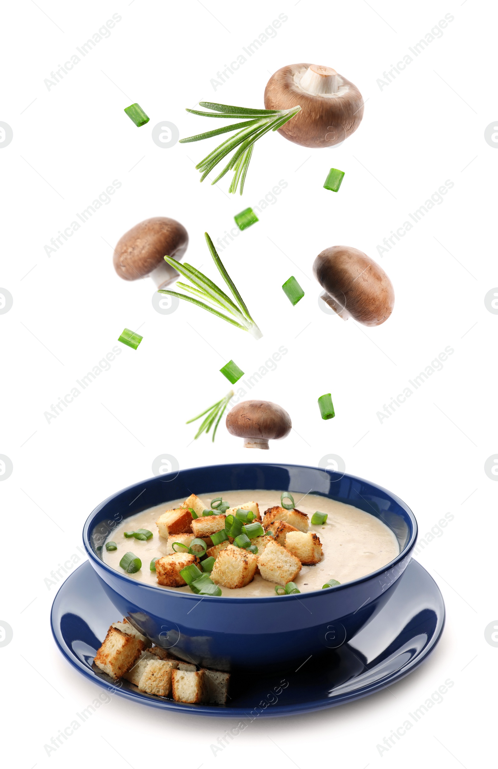 Image of Many different ingredients falling into bowl with homemade mushroom soup on white background