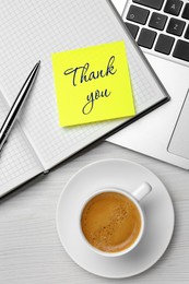 Image of Sticky note with phrase Thank You, notebook, laptop, pen and cup of coffee on white wooden table, flat lay