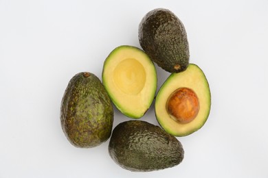 Photo of Tasty whole and cut avocados on white background, flat lay
