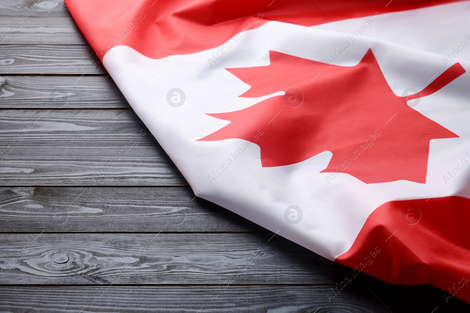 Photo of Flag of Canada on dark wooden table, closeup. Space for text