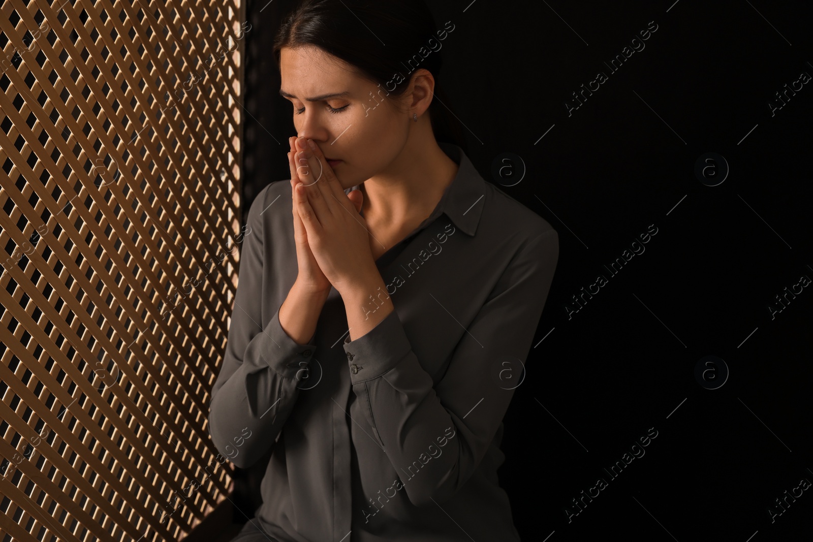 Photo of Woman praying to God during confession in booth