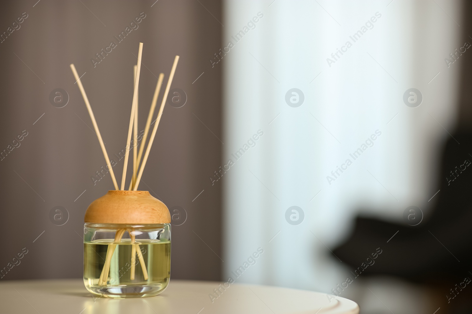 Photo of Aromatic reed air freshener on table indoors. Space for text