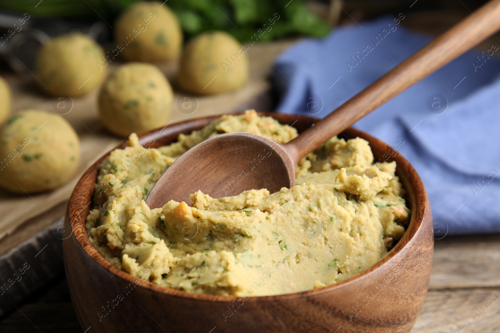 Photo of Bowl of chickpea puree with spoon on table, closeup. Falafel recipe