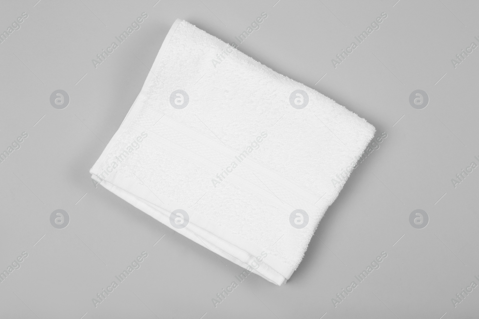 Photo of Folded white beach towel on light grey background, top view