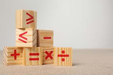 Photo of Wooden cubes with mathematical symbols on table against light background. Space for text
