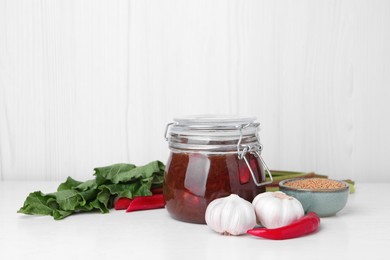 Photo of Tasty rhubarb sauce and ingredients on white table, space for text