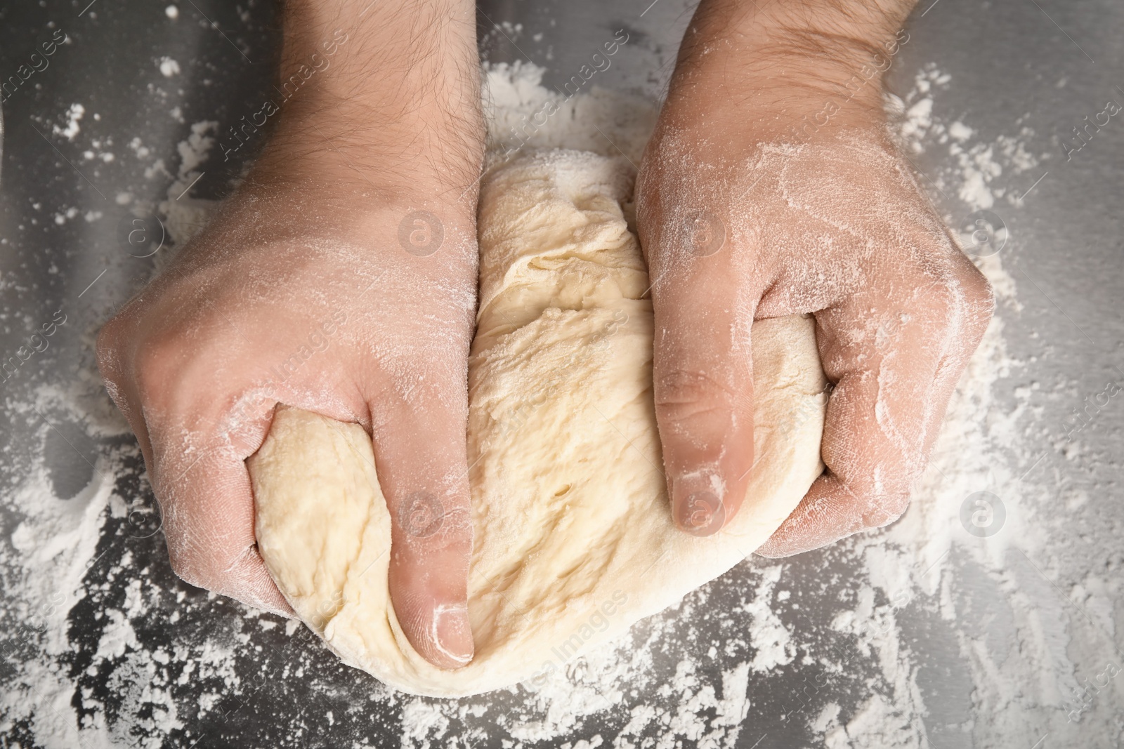 Photo of Man kneading dough for pastry on table