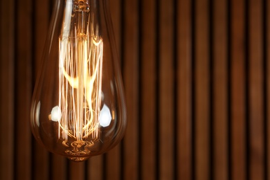 Photo of Lamp bulb near wooden wall, space for text