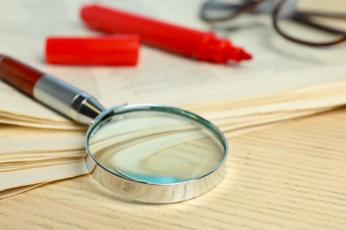 Stack of newspapers, magnifier, marker and glasses on wooden table. Search concept