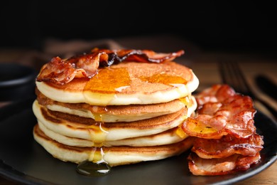 Photo of Delicious pancakes with maple syrup and fried bacon on plate, closeup