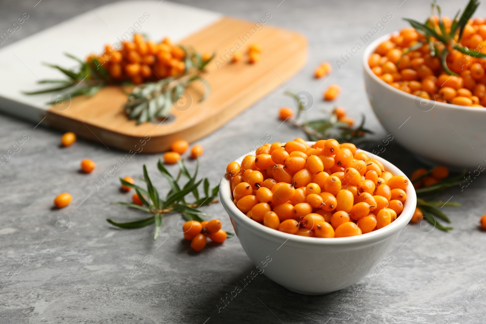 Photo of Fresh ripe sea buckthorn in bowl on grey table. Space for text