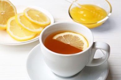 Photo of Cup with delicious immunity boosting tea, lemon and honey on white wooden table, closeup