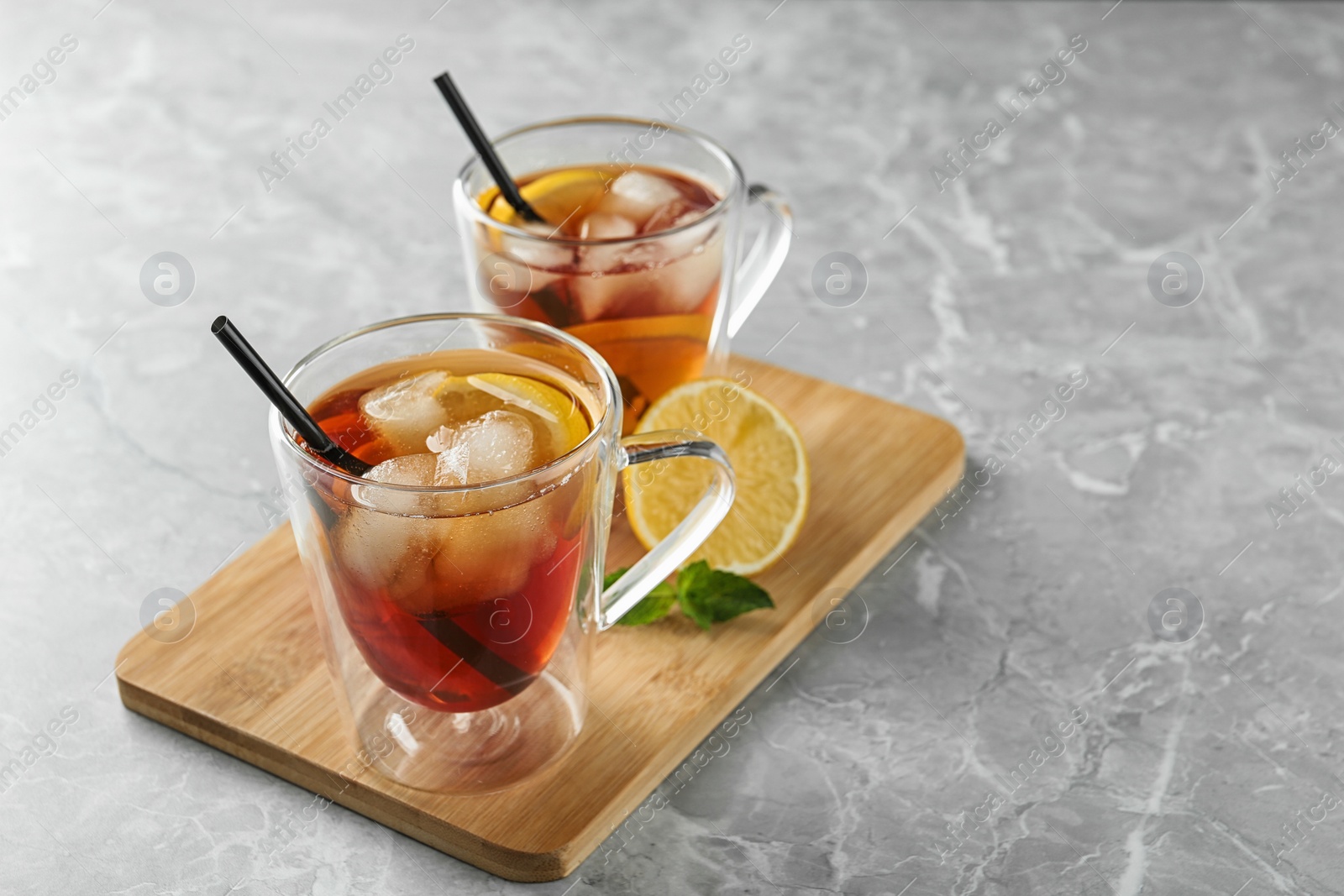 Photo of Cups of refreshing iced tea on marble table