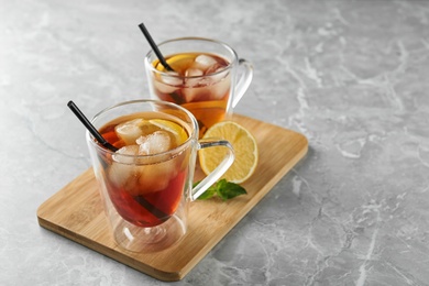 Cups of refreshing iced tea on marble table