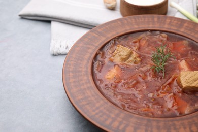 Photo of Bowl of delicious borscht on light grey table, closeup. Space for text